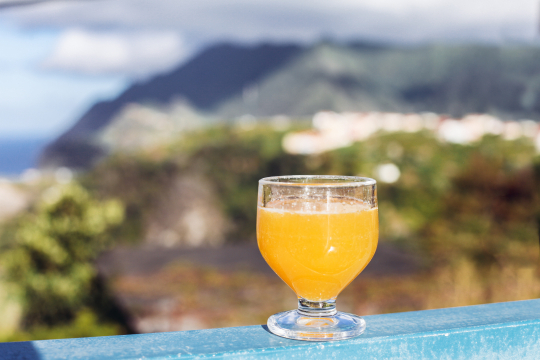 Ein Glas mit dem ber&uuml;hmten Poncha von Madeira steht auf einem Gel&auml;nder